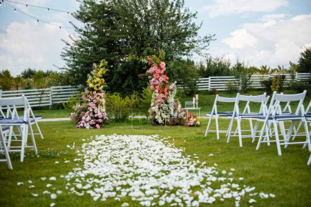 Photo for Beautiful arch decorated with colorful flowers made for wedding ceremony on nature. Stylish place for groom and bride. White chairs for guests standing around. - Royalty Free Image