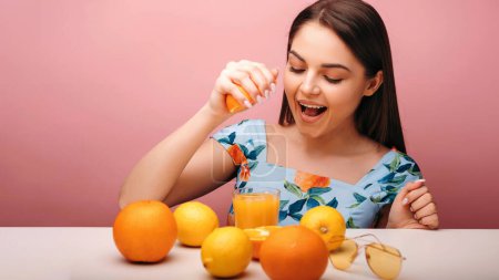 Foto de Mujer bastante caucásica en traje de verano bebiendo refrescante jugo de frutas de naranja en fondo aislado estudio rosa claro - Imagen libre de derechos