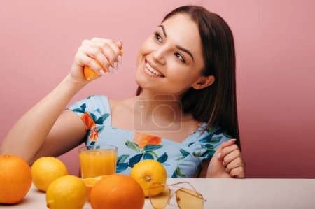Téléchargez les photos : Brunette femme préparant du jus d'orange et tenant des fruits à table. Portrait isolé en studio. Concept de mode de vie sain - en image libre de droit