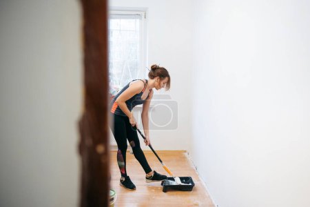 Photo for Young woman painting walls with a roller in a new house. Interior design. Renovation - Royalty Free Image