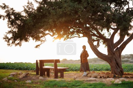 Foto de Mujer hermosa con gafas de sol y ropa de verano con estilo posando cerca del árbol de los amantes en Ayia Napa. Concepto de vacaciones, turismo y personas. - Imagen libre de derechos