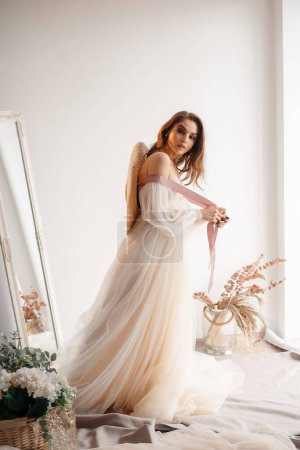 Téléchargez les photos : Beautiful bride with hat in wedding dress. Happy newlywed woman posing at the studio. Bride with wedding makeup and hairstyle. Wedding day and marriage concept - en image libre de droit