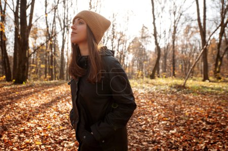 Photo for Calm positive woman enjoy autumn weather looking away and thinking about her life in forest or park full of leaves - Royalty Free Image