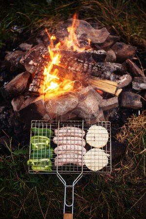 Photo for Grilling sausages. Concept of resting in the fresh air, frying sausages on the grill. Sausages, bread, vegetables barbecue - Royalty Free Image