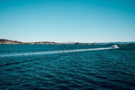 Photo for Beautiful landscape of cold North sea and island with small houses. Ferry boat in the sea. Shiny winter day in Norway. - Royalty Free Image