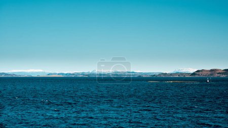 Photo for Scenic view of dark blue sea with stony island and mountains on background in Norway. Sunny spring day - Royalty Free Image