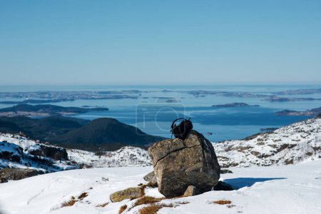 Photo for Close up travellers backpack standing on the rock. Scenic panorama winter landscape of snowy mountains and sea. Preikestolen, Norway - Royalty Free Image