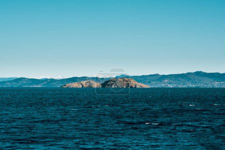 Photo for Scenic view of dark blue sea with stony island and mountains on background in Norway. View from the boat - Royalty Free Image