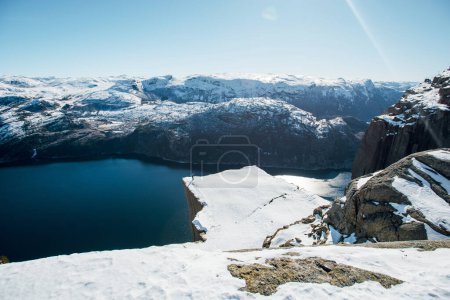 Photo for Happy man raised hands while standing near the precipice with scenic view of the water channel with mountains. Preikestolen, Lysefjord, Norway. Taveling concept. Top view. - Royalty Free Image