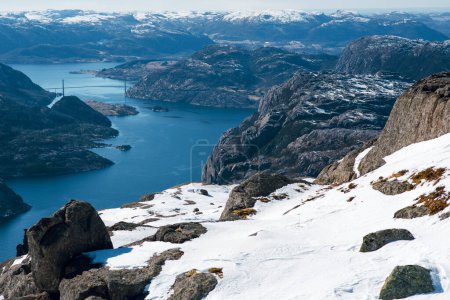 Photo for Beautiful landscape view of lsea between rocky shore with snow. Bridge in the background. Top view of the Pulpit Rock, Preikestolen. Norwegian mountains. Lysefjord, Norway - Royalty Free Image