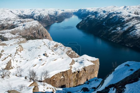 Scenic landscape of lake, river, sea with the rocky shore with mountains with snowy peaks. Top view of the Pulpit Rock, Preikestolen. Lysefjord, Norway