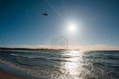 Téléchargez les photos : Hélicoptère survolant la mer avec une belle plage de sable jaune. Coucher de soleil. Norvège - en image libre de droit