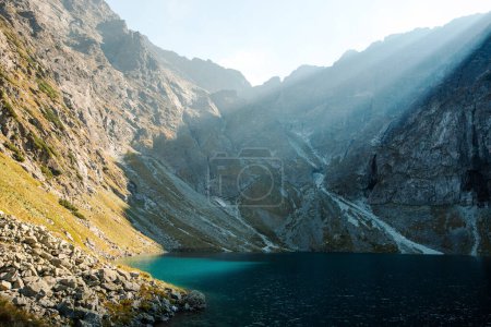 Téléchargez les photos : Vue pittoresque sur le lac Morskie Oko avec de l'eau verte avec des montagnes rocheuses et le soleil du matin. Destination voyage près de la station de ski Zakopane en Pologne. - en image libre de droit
