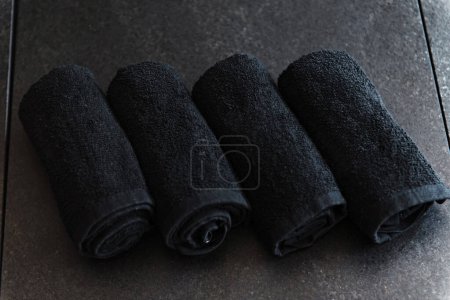 Téléchargez les photos : Serviettes roulées noires sur la table dans le salon de beauté - en image libre de droit