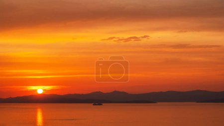 Schöner heller Sonnenuntergang und Boot, das im ruhigen Meer vor dem Hintergrund der Berge schwimmt. Unglaublicher Horizont mit malerischem Meer und buntem Himmel in der Stadt Supetar, Kroatien.