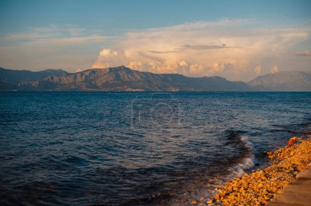 Téléchargez les photos : Paysage incroyable de la mer Adriatique sur fond de montagnes pendant le lever du soleil dans la ville de Supetar. Beau paysage marin sur la plage de galets le matin. Emplacement touristique populaire. - en image libre de droit