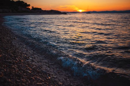Téléchargez les photos : Plage déserte de galets au coucher du soleil en Croatie. Des vagues de mer frappent le littoral de l'île de Brac. Vacances au bord de la mer Adriatique. Superbe paysage marin. - en image libre de droit
