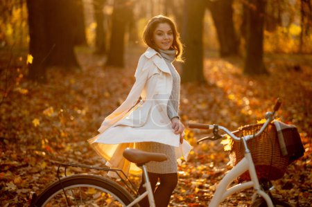 Photo for Beautiful woman with bicycle walking around the autumn leaves and having fun in park or forest. Relaxation, enjoying, solitude with nature concept - Royalty Free Image