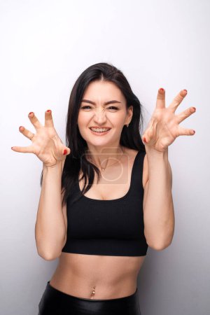 Téléchargez les photos : Brunette young woman wearing casual clothes smiling funny doing claw gesture as cat, aggressive and sexy expression. Stock photo - en image libre de droit