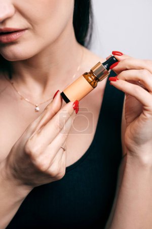 Téléchargez les photos : Closeup view of the beautiful young woman moisturises her skin with a serum. Caring for the skin and essential oil for anti-aging therapy concept - en image libre de droit