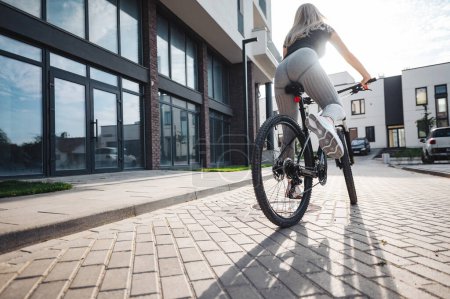 Photo for Close up of young woman wearing sport clothes and sneakers riding bike on fresh air. Focus on strong female legs. Active lifestyles on young person. - Royalty Free Image