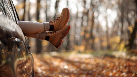 Photo for Cropped view of the woman legs from the auto window during the autumn day. Autumn forest journey by car concept - Royalty Free Image