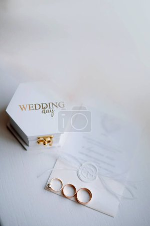 Téléchargez les photos : Anneaux de mariage avec boîte blanche et invitation de caligraphie sur la table. Détails de mariage sur flatlay - en image libre de droit