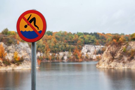 Photo for No swimming sign on the bank of the Zakrzowek quarry at rainy autumn day. Popular lake in Krakow, Poland - Royalty Free Image