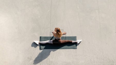 Téléchargez les photos : Vue complète de la forme de la jeune femme faisant de l'exercice d'étirement. Modèle de remise en forme exercice le matin à l'extérieur. Photo de stock - en image libre de droit