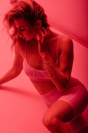 Photo for Attractive confident young woman posing in sexy comfortable underwear in red neon light studio. Woman body concept - Royalty Free Image
