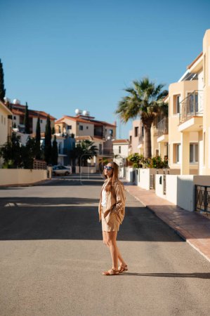 Foto de Hermosa joven morena con cuerpo perfecto posando en la ciudad de verano. Mujer alegre en gafas de sol caminar en la calle en estilo casual - Imagen libre de derechos