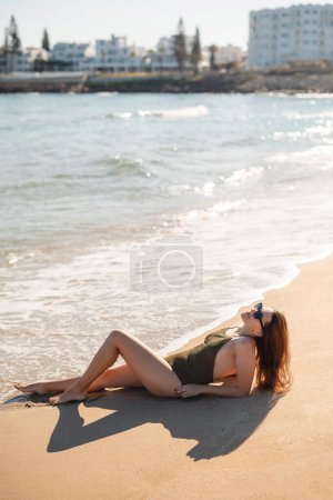 Téléchargez les photos : Femme élégante allongée sur la plage. Jeune femme souriante en vacances profiter de la brise de mer. attrayant belle fille week-end concept - en image libre de droit