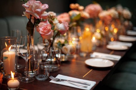Foto de Hermosa mesa de ajuste para la boda u otra cena evento abastecido. Velas borrosas con luces cálidas en el fondo - Imagen libre de derechos