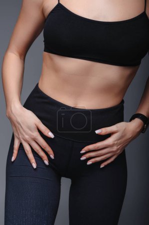 Photo for Close-up view of a woman wearing black sportswear. Studio shot of perfect woman figure in sport top and tight leggings - Royalty Free Image