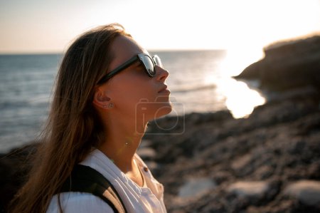 Photo for Close up portrait of a young traveler girl in sunglasses on the seashore at beautiful sunset - Royalty Free Image