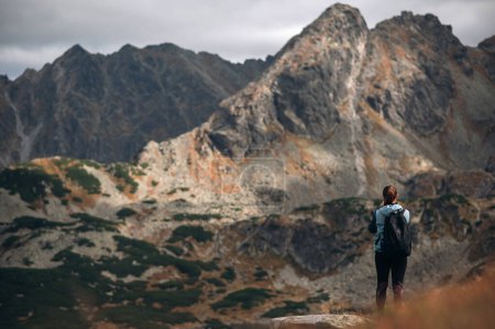 Téléchargez les photos : Vue arrière de la jeune voyageuse avec sac à dos debout rebondit belles montagnes Tatra en Pologne - en image libre de droit