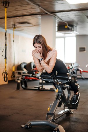 Photo for Full length portrait of young woman doing hyperextension at gym. Slim female flexing back and abdominal muscles on bench, looking down. Concept of sport. - Royalty Free Image