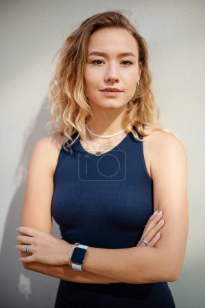 Photo for Blonde curly woman posing arms crossed near the wall after good sportive training. People and sport concept. Close up portrait - Royalty Free Image