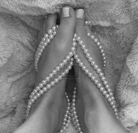 Foto de Vista lateral de los pies de las mujeres pequeñas con perlas envueltas alrededor de los dedos de los pies y arcos - Imagen libre de derechos