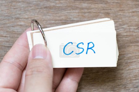 Photo for Hand hold flash card with handwriting in word CSR (Abbreviation of corporate social responsibility) on wood background - Royalty Free Image