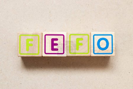 Téléchargez les photos : Bloc de lettres couleur dans le mot FEFO (Abréviation du premier arrivé à expiration) sur fond bois - en image libre de droit