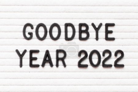 Foto de Carta de color negro en la palabra adiós año 2022 sobre fondo de tablero de fieltro blanco - Imagen libre de derechos