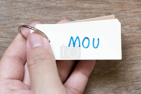 Foto de Hand hold flash card with handwriting in word MOU (Abbreviation of memorandum of understanding) on wood background - Imagen libre de derechos