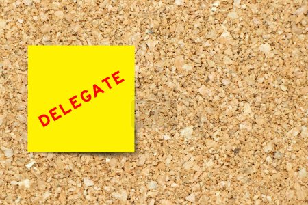 Téléchargez les photos : Yellow note paper with word delegate on cork board background with copy space - en image libre de droit