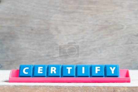 Letra del alfabeto del azulejo con palabra certifican en estante de color rojo sobre fondo de madera