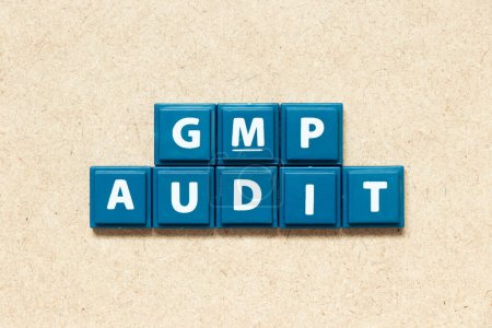 Tile alphabet letter in word GMP (Abbreviation of good manufacturing practice) audit on wood background