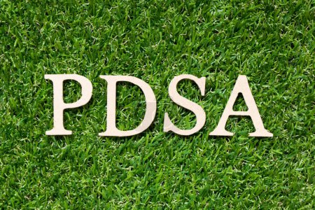 Téléchargez les photos : Lettre alphabet en bois dans le mot PDSA (Abréviation du plan do study act) sur fond de gazon vert artificiel - en image libre de droit