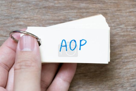 Photo for Hand hold flash card with handwriting in word AOP (abbreviation of Annual Operating Plan or Aspect-oriented programming) on wood background - Royalty Free Image
