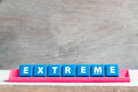 Foto de Letra del alfabeto del azulejo con palabra extrema en estante de color rojo sobre fondo de madera - Imagen libre de derechos