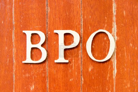 Foto de Letra del alfabeto en la palabra BPO (Abreviatura de la externalización del proceso de negocio) en el fondo de la placa de madera de color rojo viejo - Imagen libre de derechos
